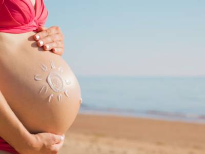 Donna incinta al sole sulla spiaggia