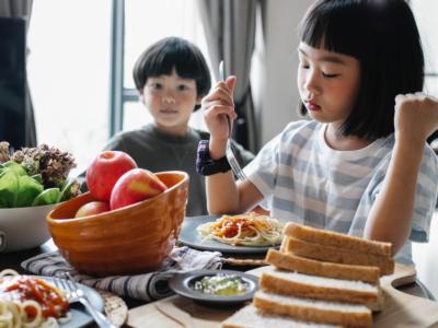 Bambini che mangiano pasta e pane