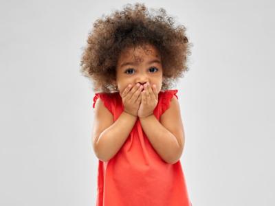 Bambina con le mani davanti alla bocca