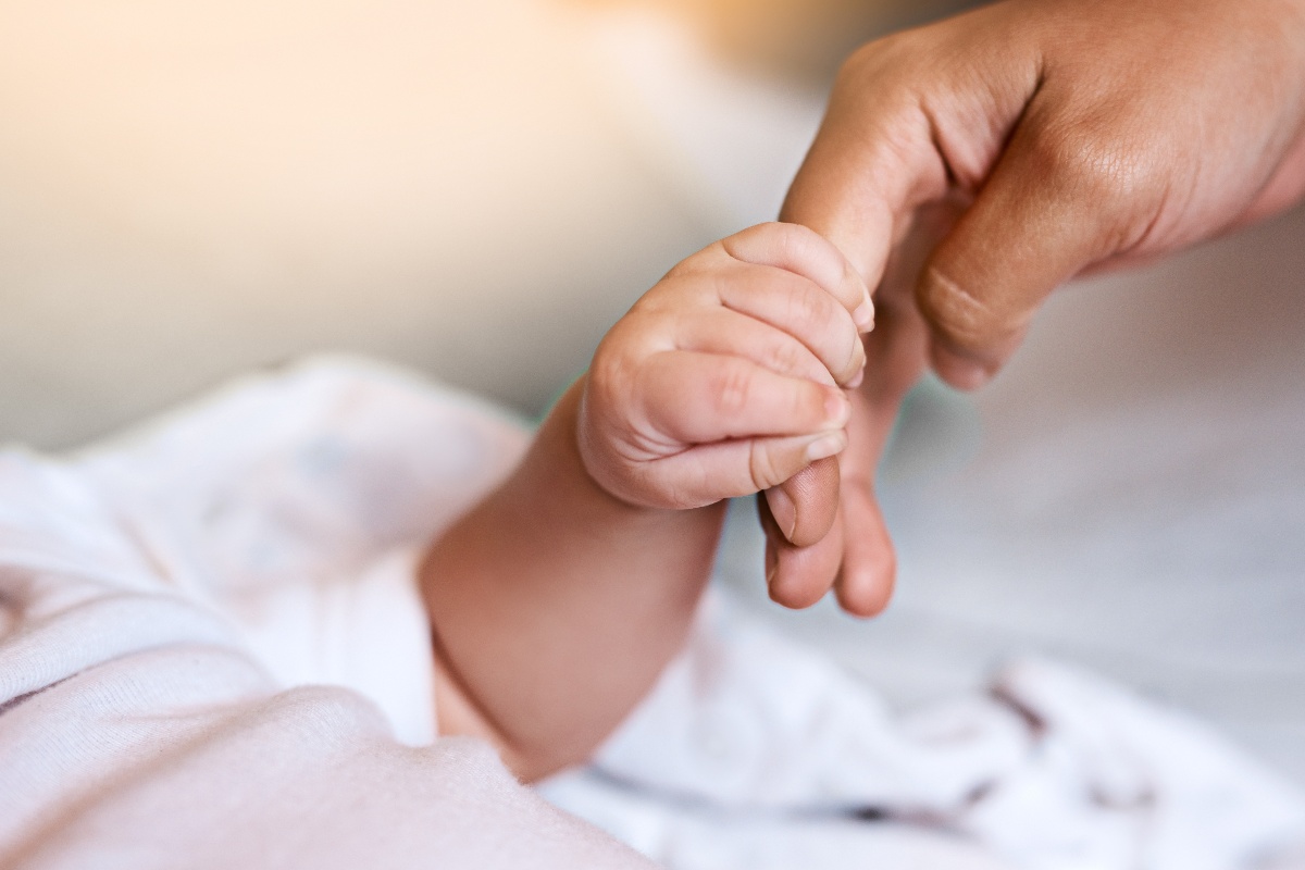 Neonato stringe la mano del genitore