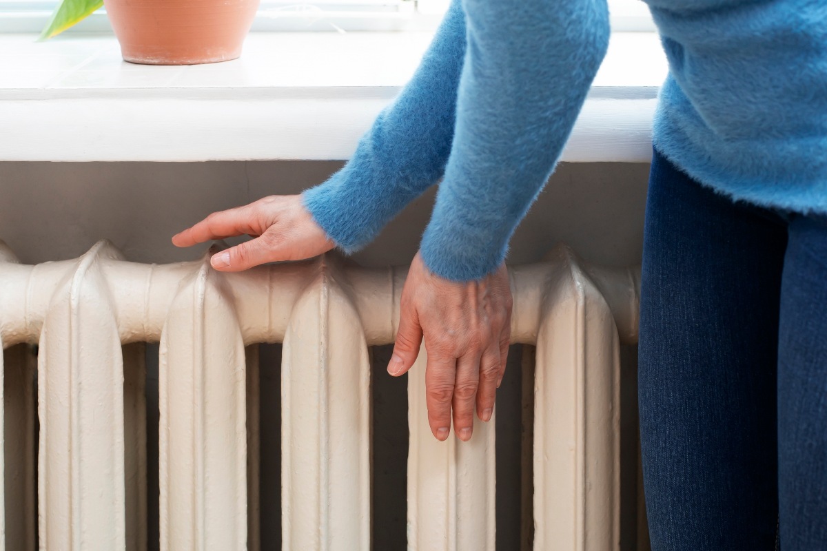 donna che appoggia le mani sul termosifone