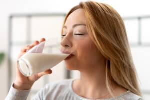 donna che beve latte da un bicchiere di vetro