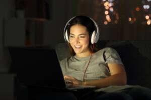 ragazza che guarda il pc con le cuffie al buio