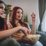 Ragazze sul divano con i popcorn che guardano un film