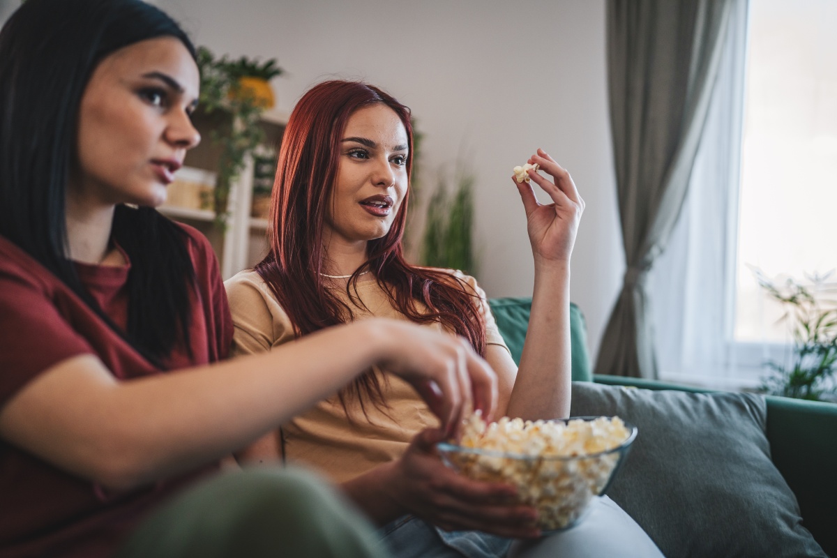 Ragazze sul divano con i popcorn che guardano un film