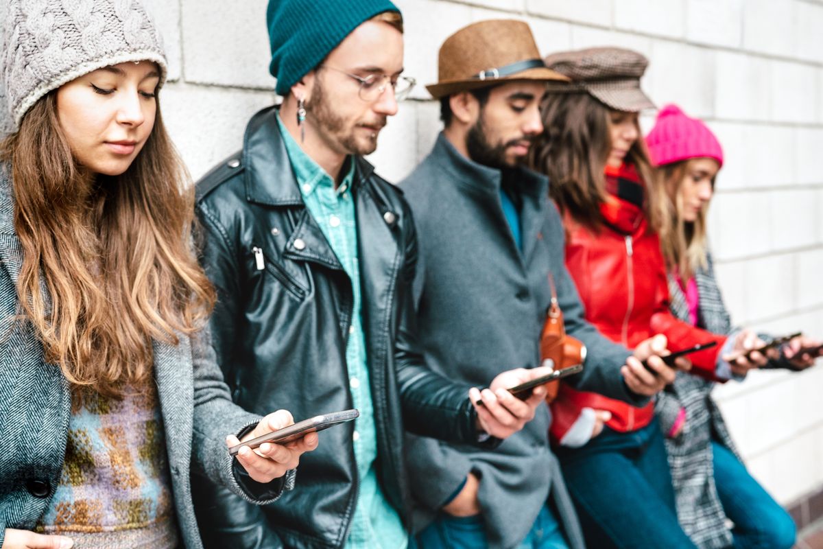 ragazzi con lo smartphone appoggiati al muro