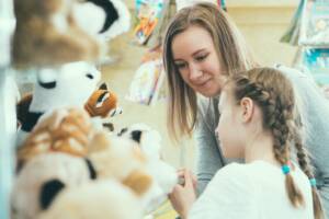 Bambina e mamma scelgono peluche in un negozio di giochi