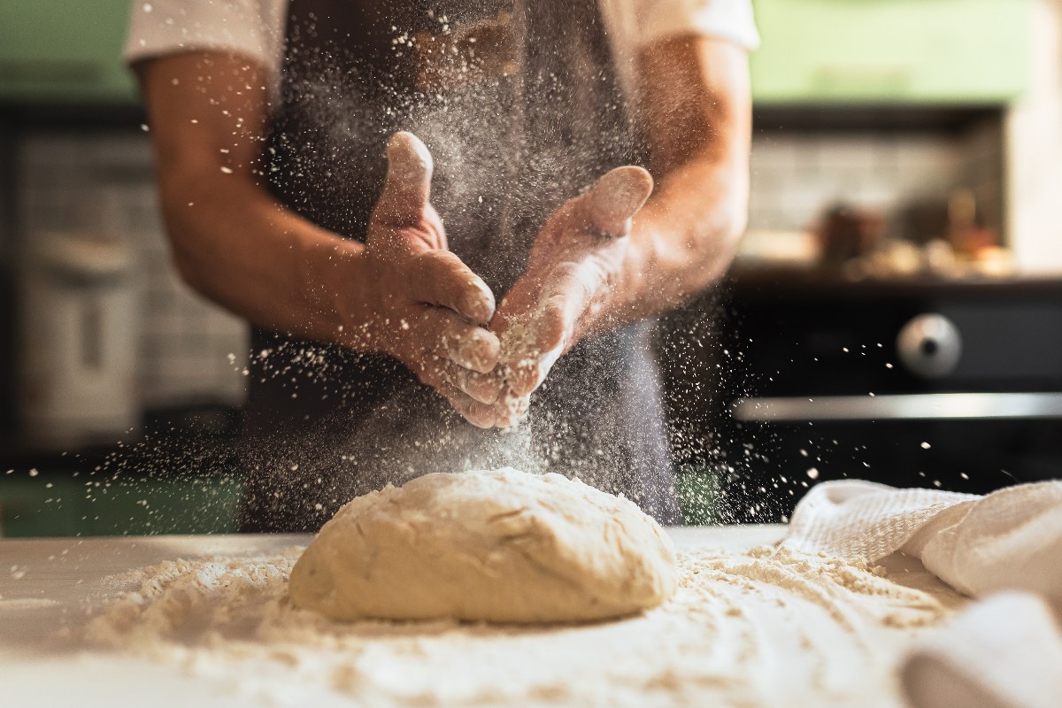 Cuoco prepara l’impasto della pizza con farina