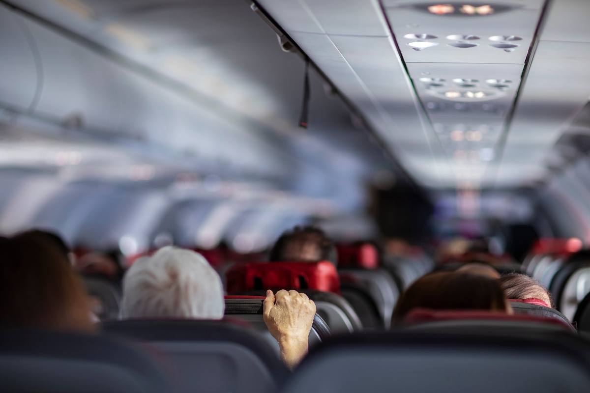 interno di un aereo durante una turbolenza con passeggero che si aggrappa al sedile davanti