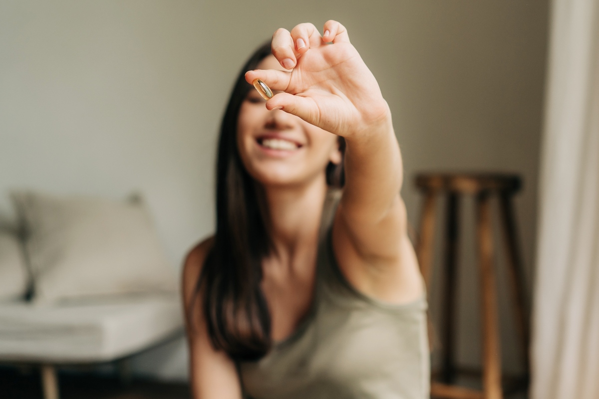 Donna sorridente mostra una pastiglia di integratore naturale