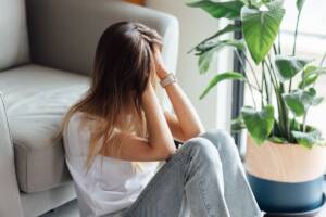 ragazza disperata seduta a terra con le mani tra i capelli